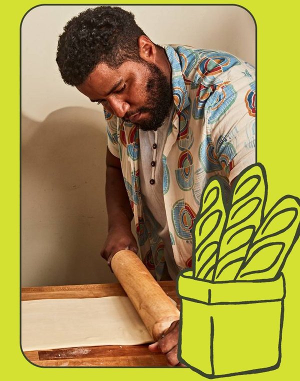 Chef Bryan Ford rolling out dough beside a basket of baguettes