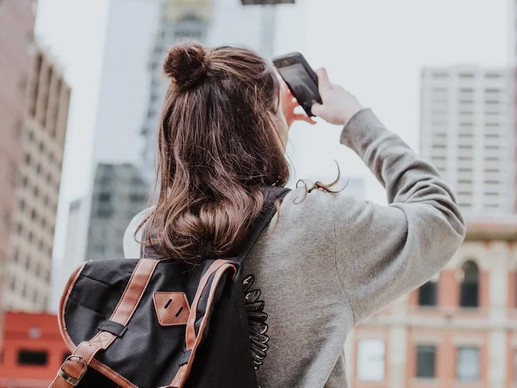 Woman with a small backpack walking through a city street, seen from behind