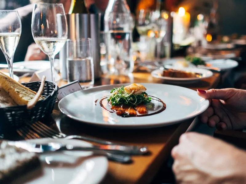 Restaurant table with a plated salad, a bread basket and glasses of white wine