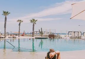 Woman sitting at the edge of a hotel pool under palm trees