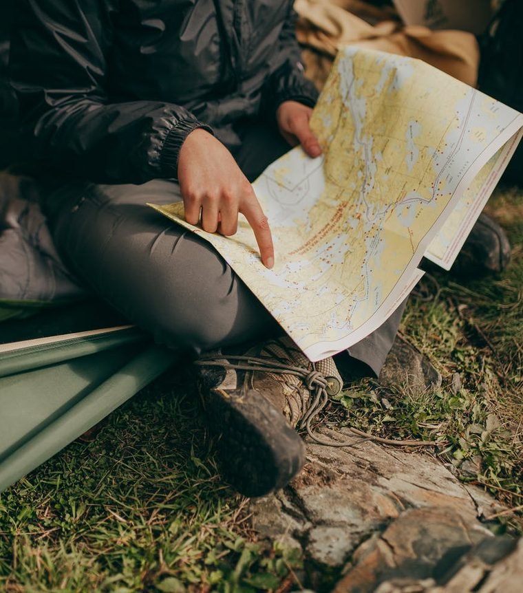 Trail map spread open on a traveller's knees at camp