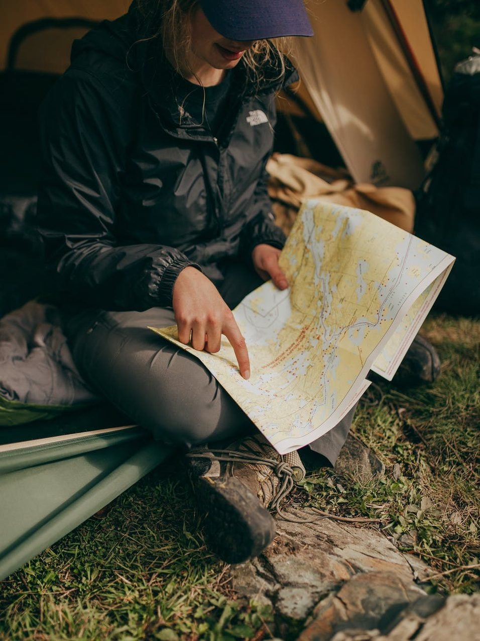 Traveller in a rain jacket studying a trail map inside a tent