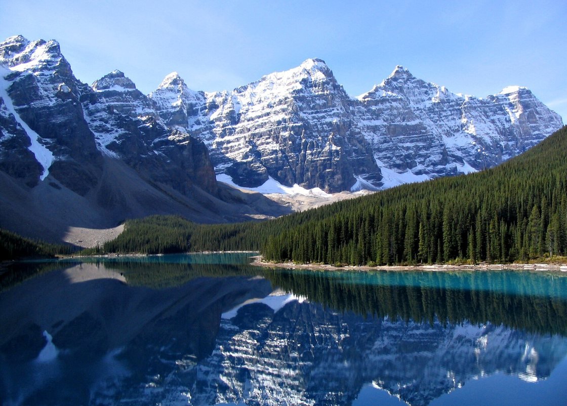 Turquoise mountain lake surrounded by pines and snow-capped peaks