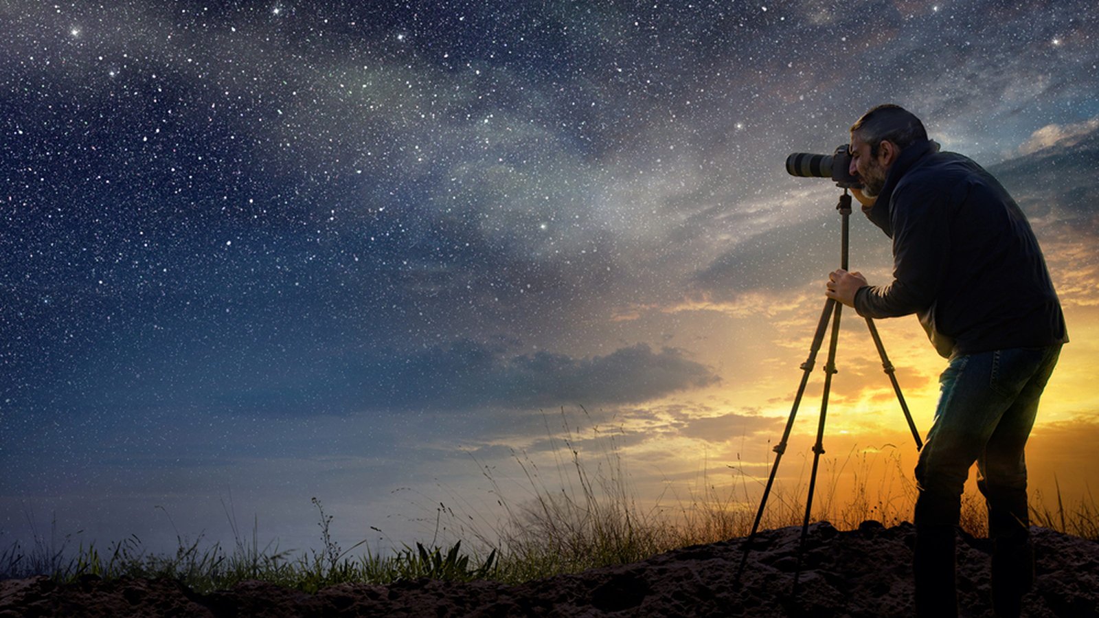 Photographer with a tripod shooting a starry sky above a sunset horizon