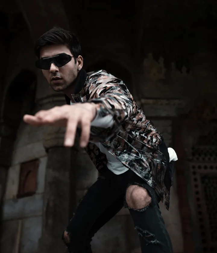 Man in a patterned jacket and sunglasses leaning out of a stone archway