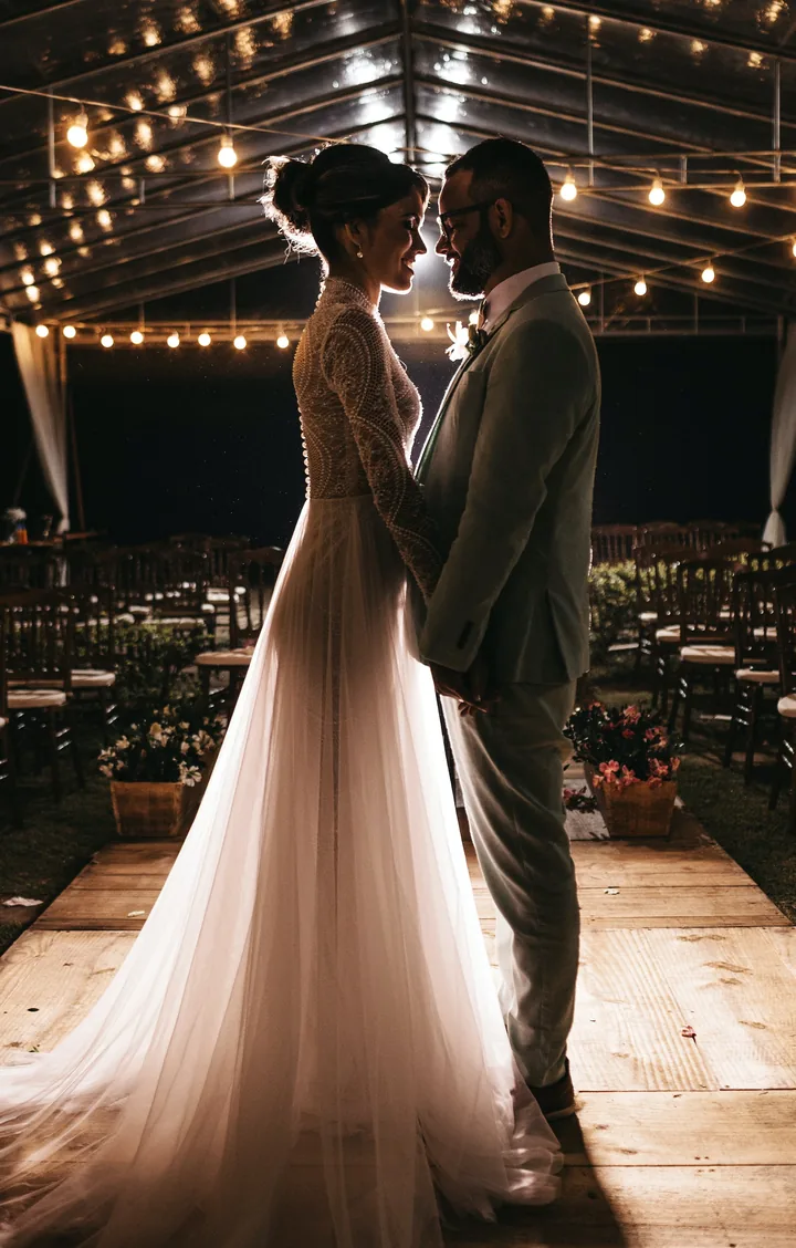 Bride and groom holding each other under warm string lights